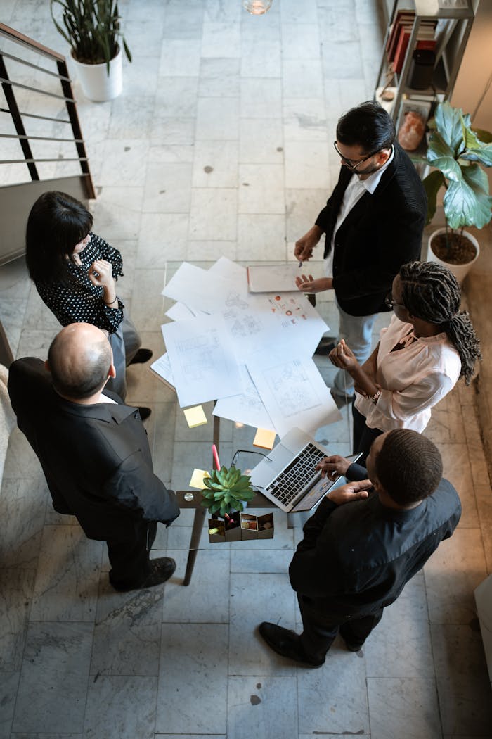 Top view of a diverse team discussing plans over documents and laptops in an office setting.